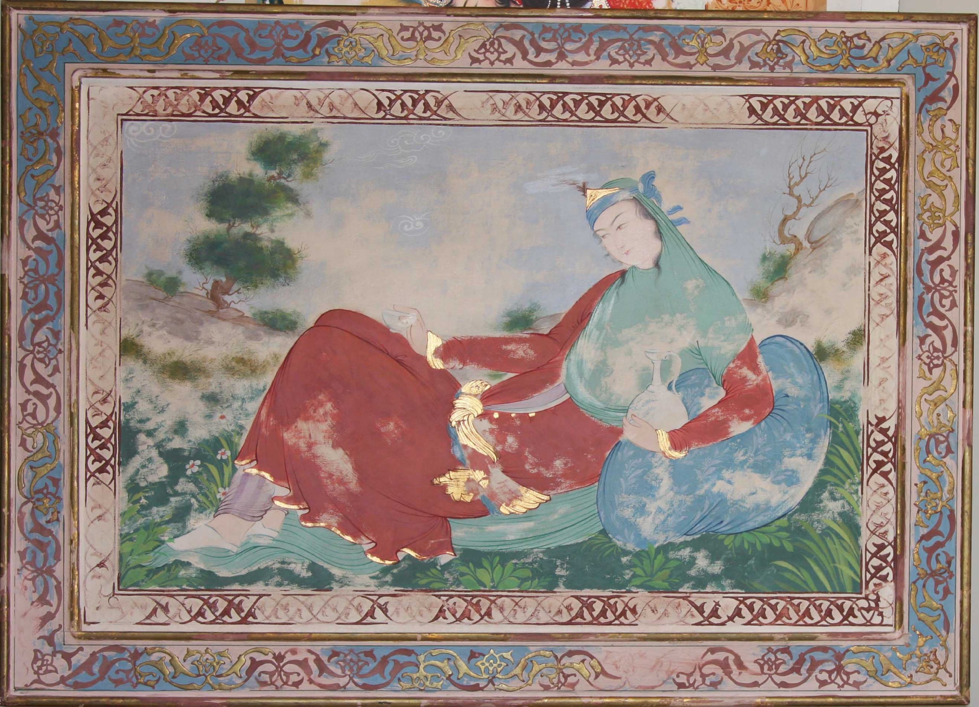 Persian miniature of a reclining figure in a landscape with an ornate painted border